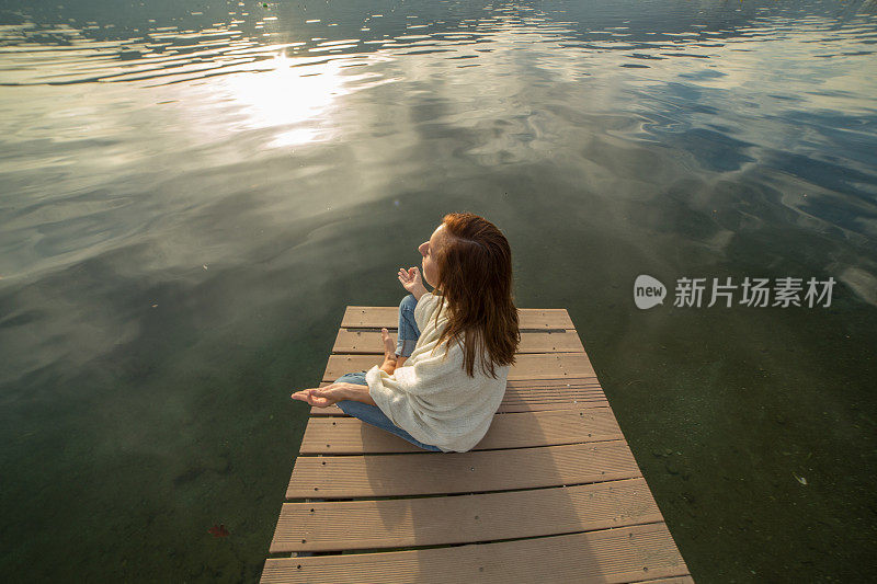 一个女人在湖边的码头上练习瑜伽