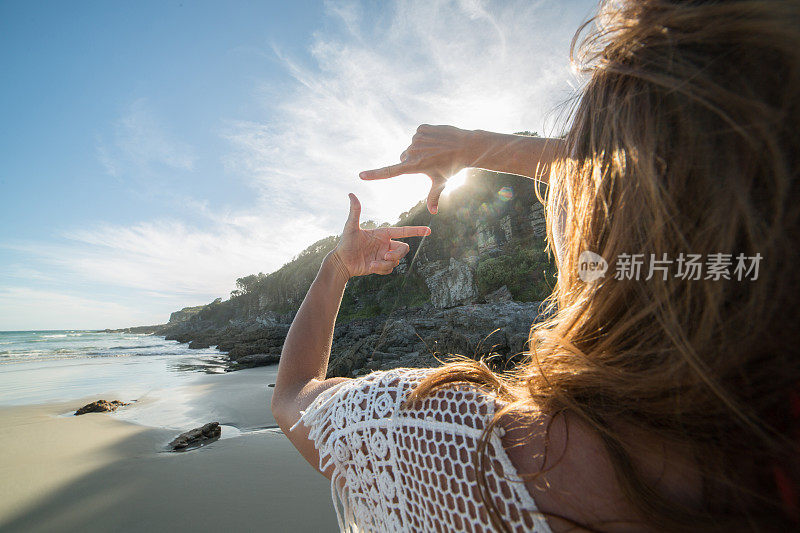 沙滩上的年轻女子对着阳光指指点点