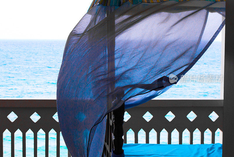 和平绿洲:蓝色的床和微风的窗帘俯瞰大海