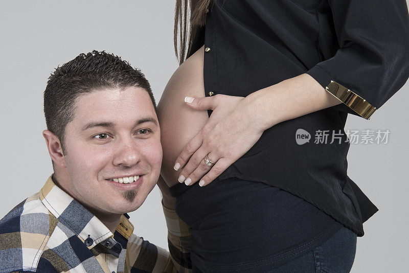 男人头靠在怀孕妻子的肚子上的肖像