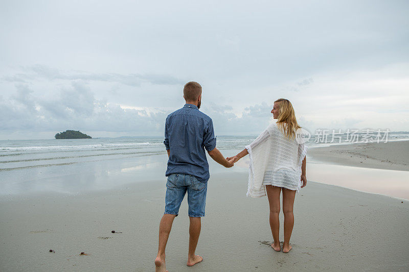 一对年轻夫妇在海滩上散步