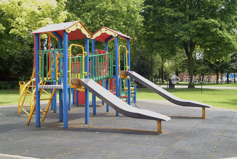 两个滑梯在儿童游乐场的公园与树木