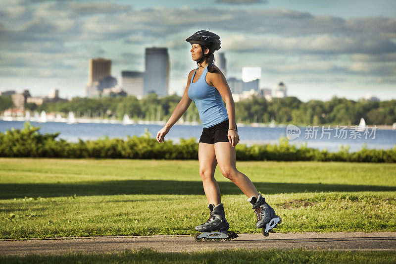 健康的年轻女子在城市公园穿着直排轮滑运动