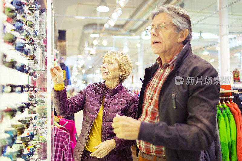 快乐的老年夫妇在商店试穿太阳镜