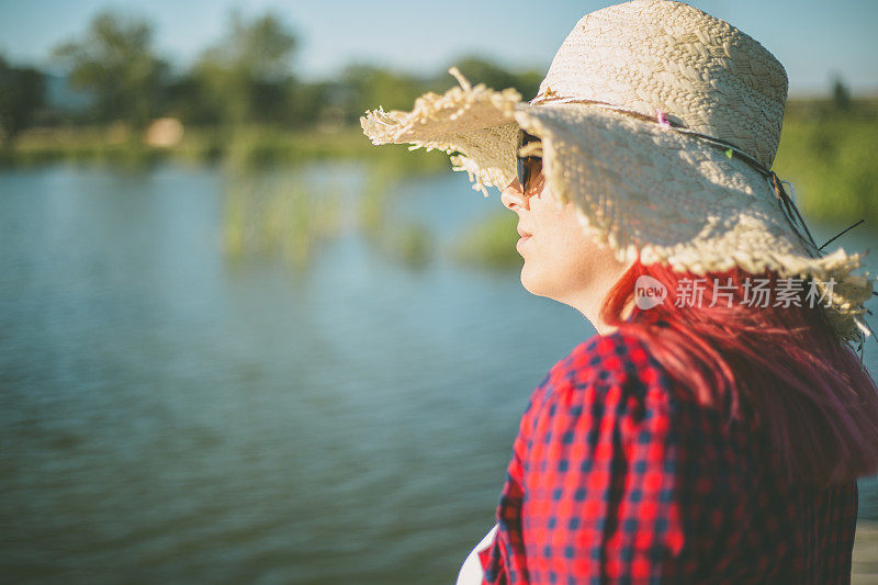 美丽的女人站在户外湖边的木码头上