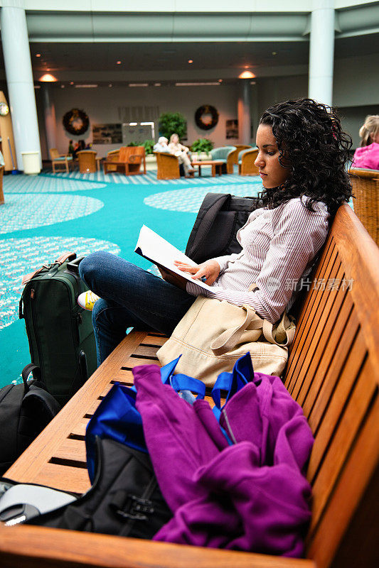 十几岁的女孩在机场候机时看书