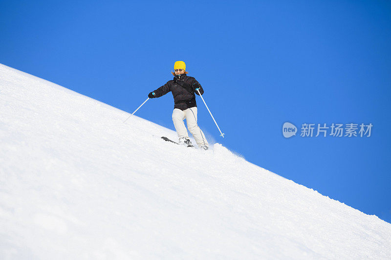 在阳光明媚的滑雪胜地滑雪的中年妇女滑雪