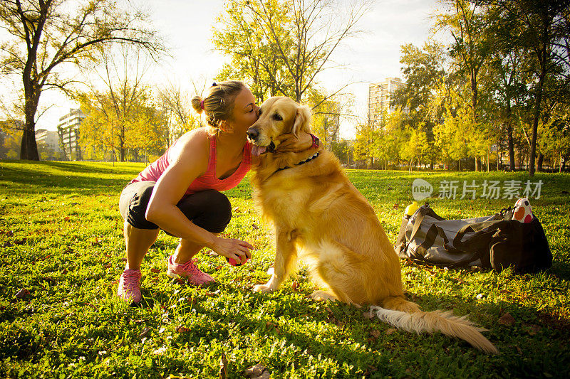 女跑步者亲吻她的狗，在公园里