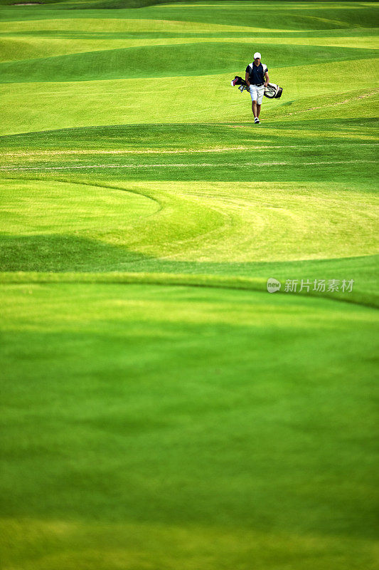 远处一名男性高尔夫球手正从球道上走下来