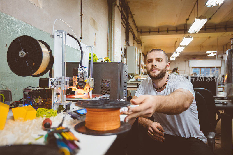 一个年轻人在建筑车间里使用3D打印机