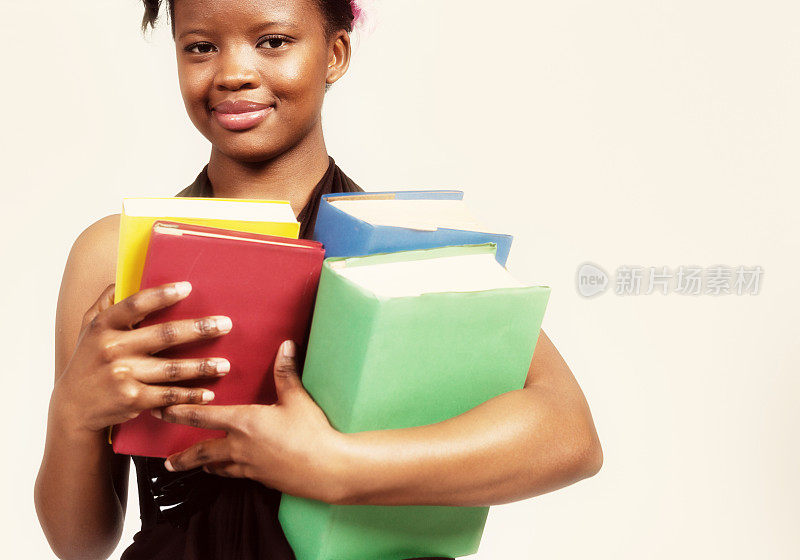 一个年轻的女人拿着一堆书微笑着