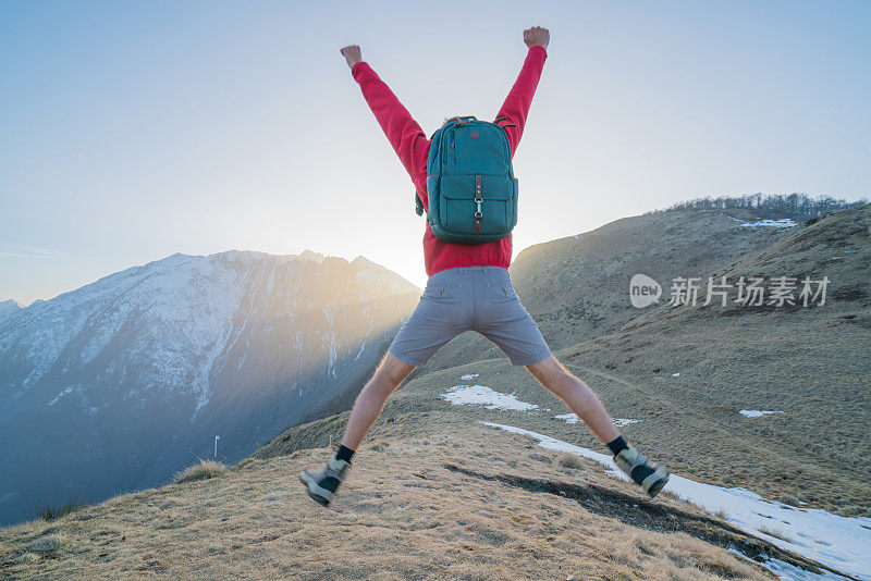 徒步旅行者在空中跳得很高，在山顶