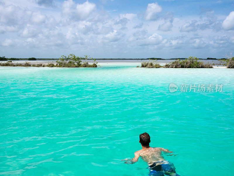 在墨西哥巴卡拉泻湖海盗运河碧绿的水中游泳的年轻人