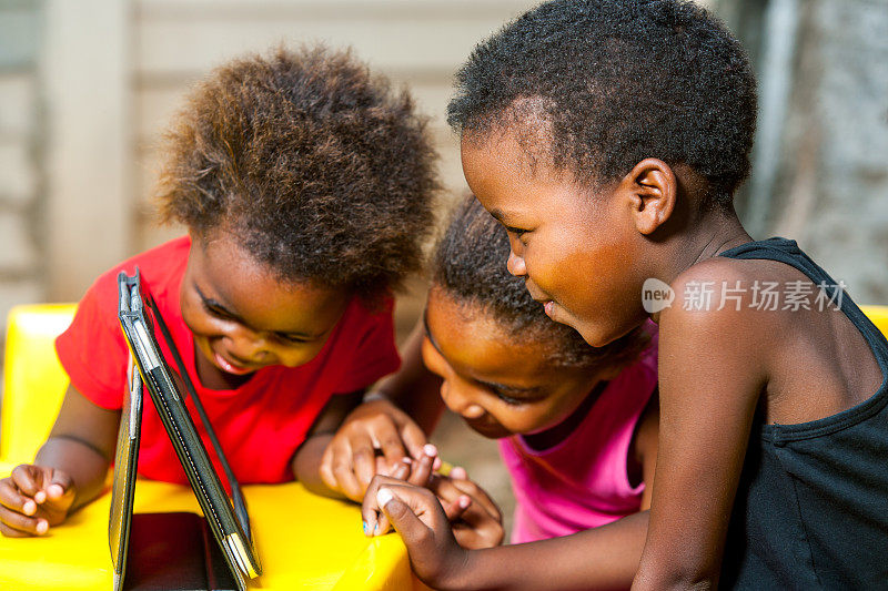 三个非洲小孩在玩平板电脑。