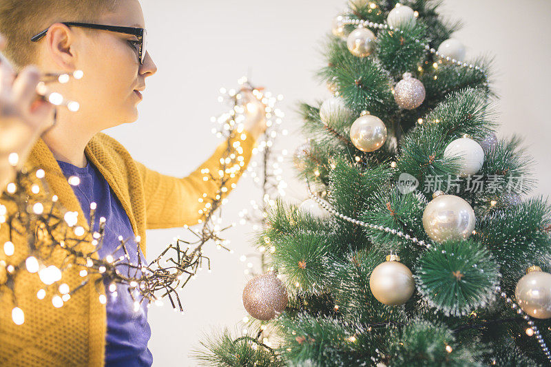 圣诞节、寒假和人们的观念——快乐的年轻女子在家里装饰圣诞树