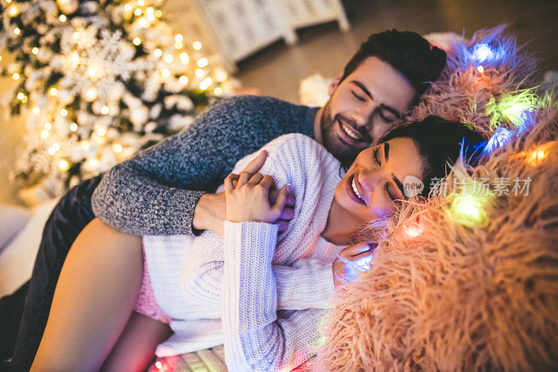 激情浪漫的情侣在新年前花时间在家里美丽的圣诞树附近