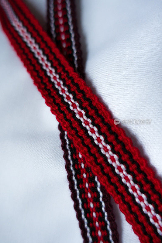 两个交叉的窄编织带在红色，紫色，黑色和白色的民族图案