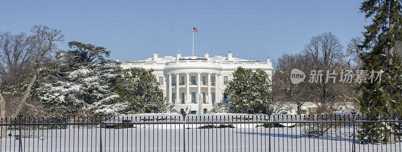 在明亮的蓝天下，白宫和庭院被白雪覆盖。