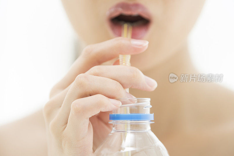 一个女人用吸管吸着塑料瓶里的东西。