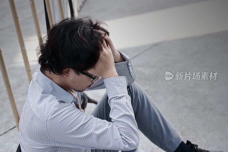 沮丧压力年轻的亚洲商人感到失望或疲惫的工作在外面的办公室。