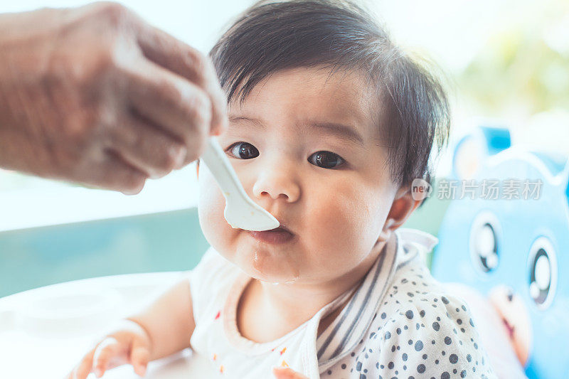 祖母在家用勺子喂可爱的亚洲女婴