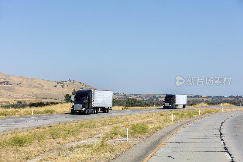 在美国加州州际公路上，两辆半挂车运载着拖车