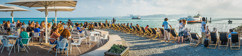 游客享受温暖的阳光在海滨咖啡馆酒吧葡萄牙里斯本