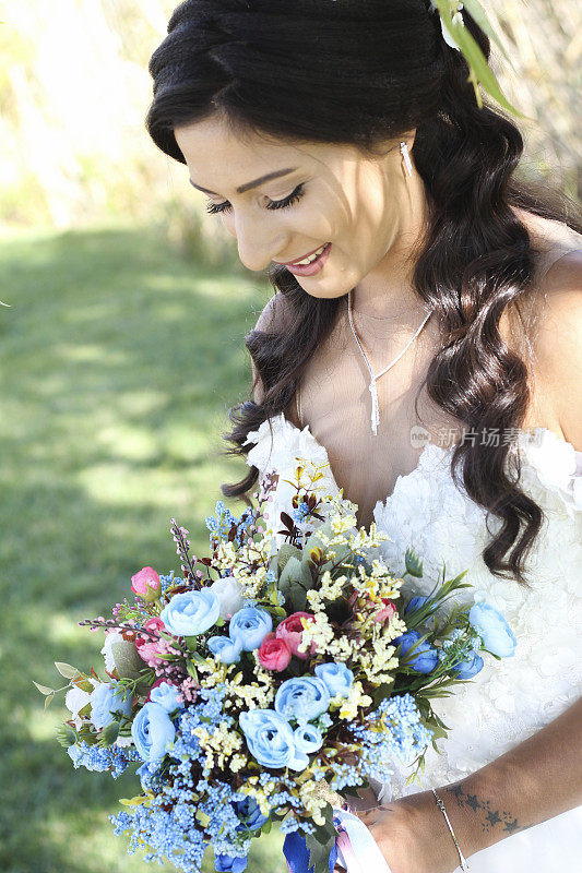 新娘手捧紫色和白色的婚礼花束。新娘捧花束