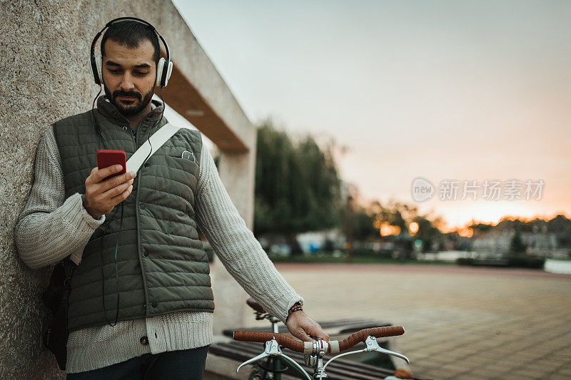 男人戴着耳机在城市街道上听音乐和使用电话