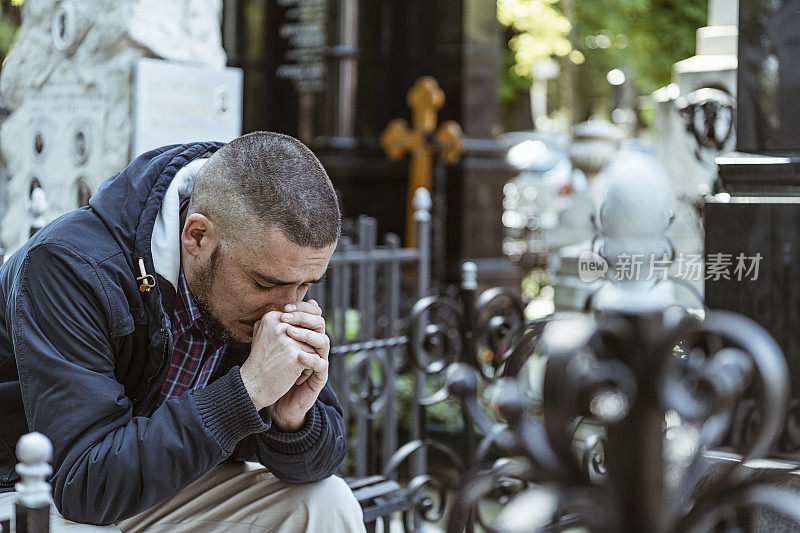 情绪紧张的黑衣男子在他家人的墓前