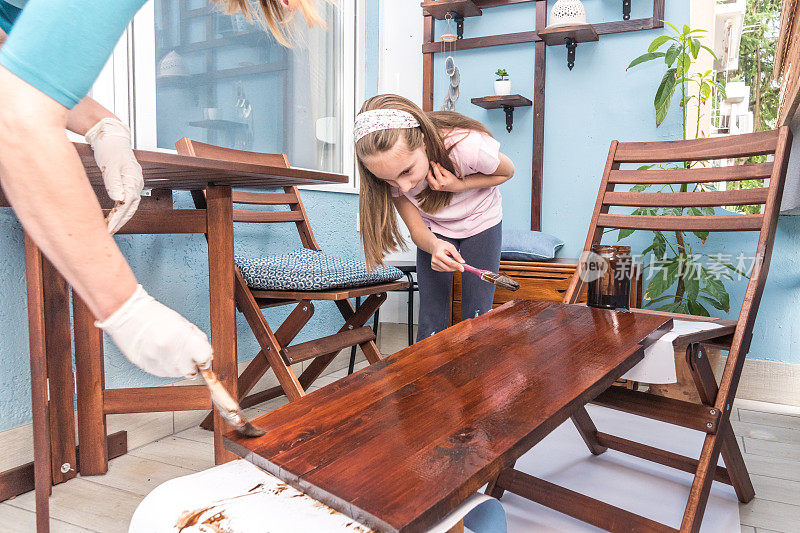 阳台上的勤杂工在女儿的帮助下画木板