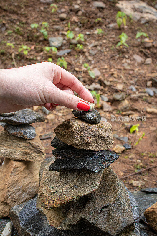 一个女孩的手堆起小石头的特写。