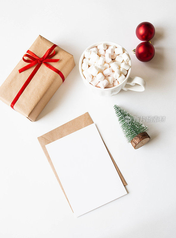 白色马克杯，热饮和棉花糖，纸卡的信件，信封和圣诞装饰在白色的背景。前视图。本空间