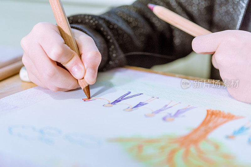 小学年龄的女孩在家做家庭作业，在她的作业簿上画画