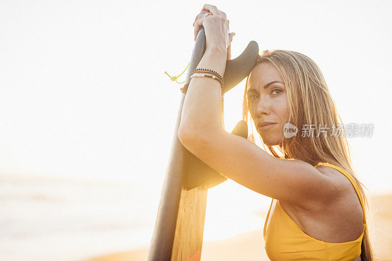 海滩上有个带着冲浪板的漂亮女人