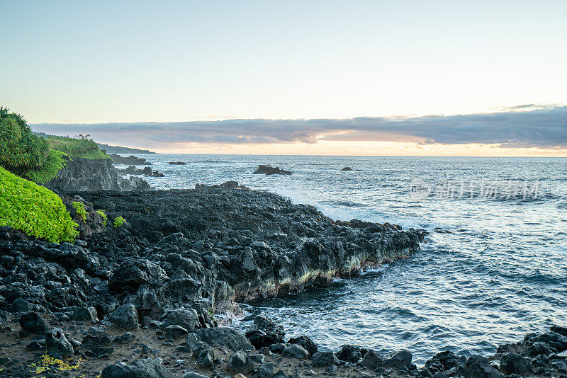 日出时的岩石海岸线，海浪拍打着夏威夷毛伊岛的悬崖