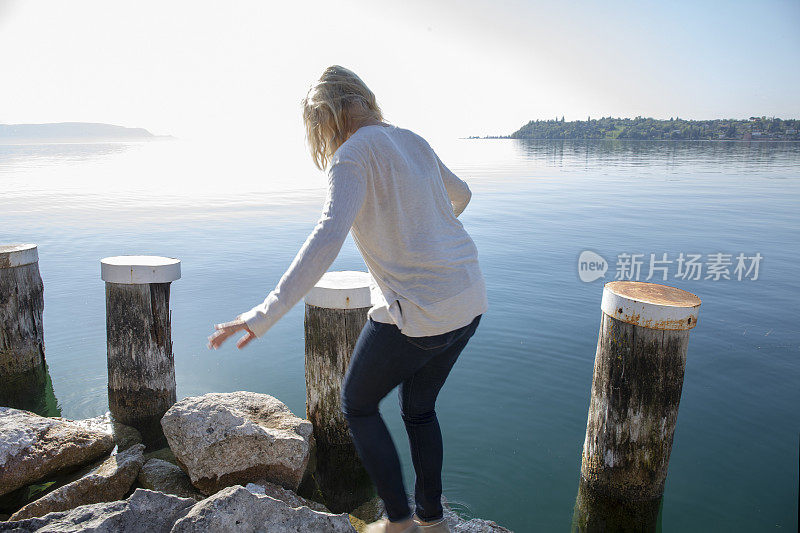 日出时分，一名女子踏上了湖面上的岩石栈桥