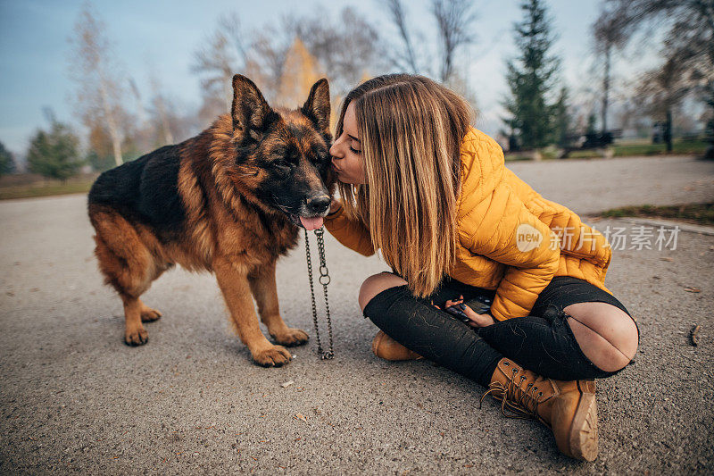 公园里有个年轻女人和一只德国牧羊犬