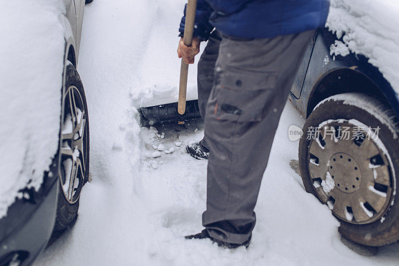 一位老人正在他的车旁扫雪