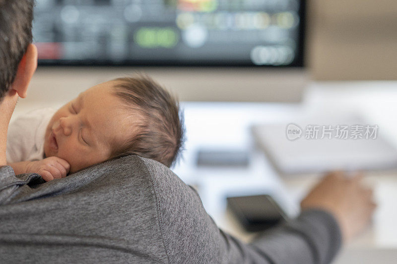 新爸爸一边工作一边抱着刚出生的宝宝