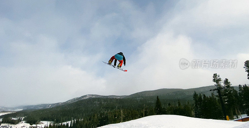 一个滑雪板在完整的冬季装备试图在一个滑雪板在博尔德附近的埃尔多拉滑雪度假村上跳跃的把戏，科罗拉多州在一个明亮，阳光明媚的冬日