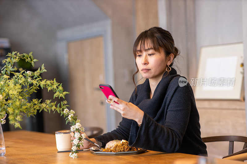 在家里吃羊肉咖喱时用智能手机的女人