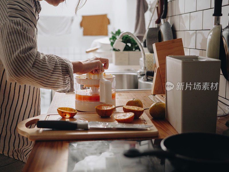 千禧一代亚洲妇女在早上做橙汁