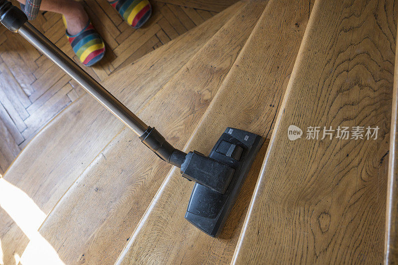 男人用吸尘器清扫家里的木楼梯