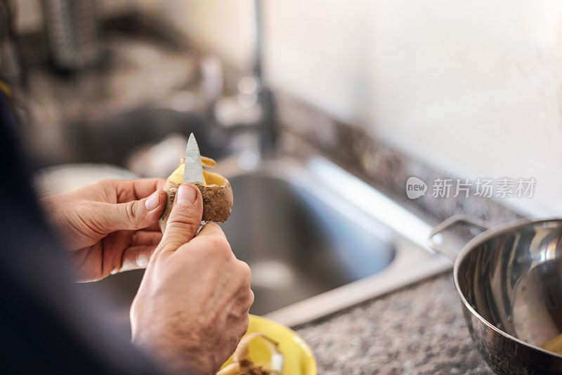 隔离烹饪:一名男子在煮土豆之前剥土豆皮