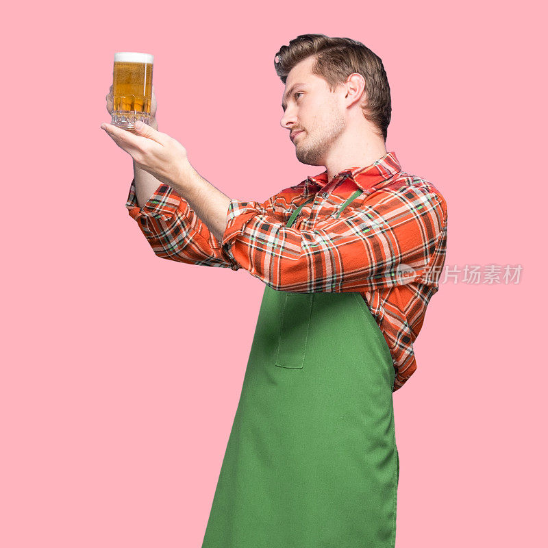 酿酒师-白人年轻男性体力劳动者站在有色背景前，穿着衬衫，拿着饮料