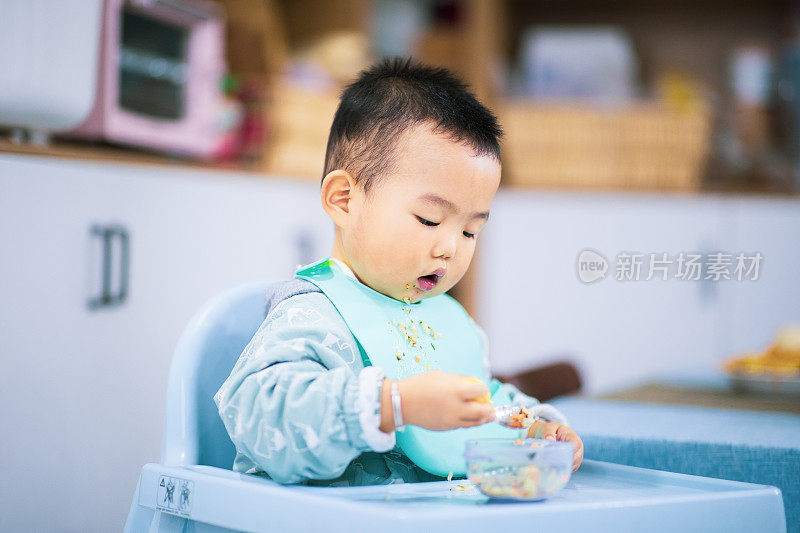 小男孩坐在高椅子上吃东西