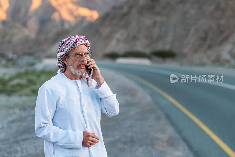 一个阿拉伯人在沙漠的山路上打电话