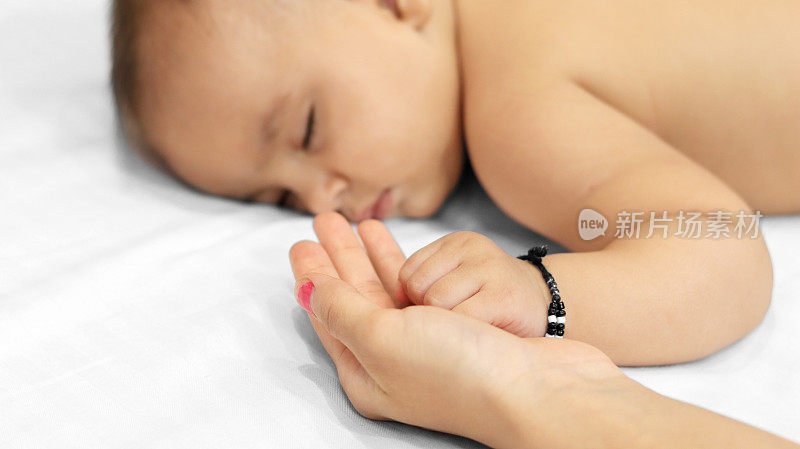 婴儿抱着妈妈的手睡觉