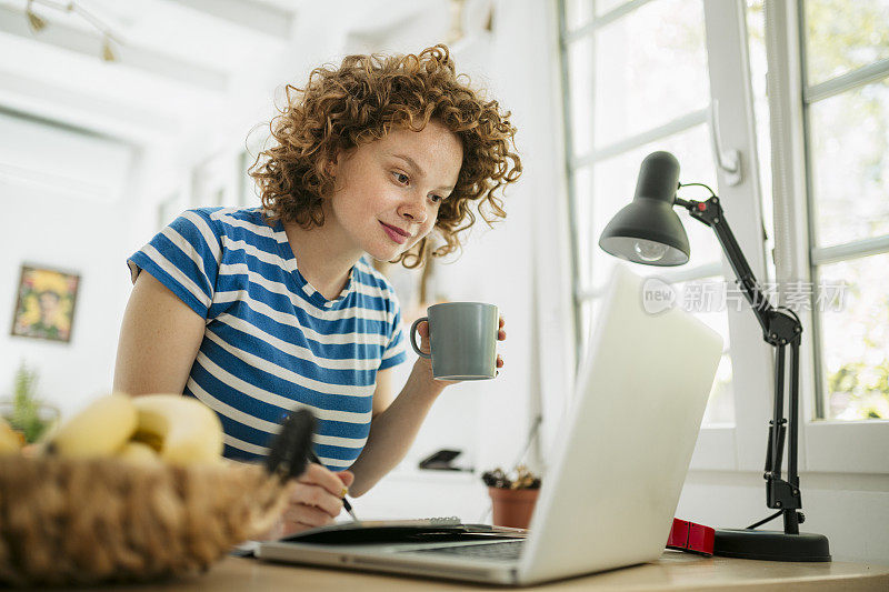 一个年轻漂亮的女人在家工作的侧视图